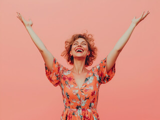 Joyful woman raising her arms, wearing a floral dress, standing against a vibrant pink background, capturing a cheerful and energetic moment