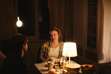 Happy young couple in love celebrate Valentine's Day in their cozy apartment in subdued warm lighting
