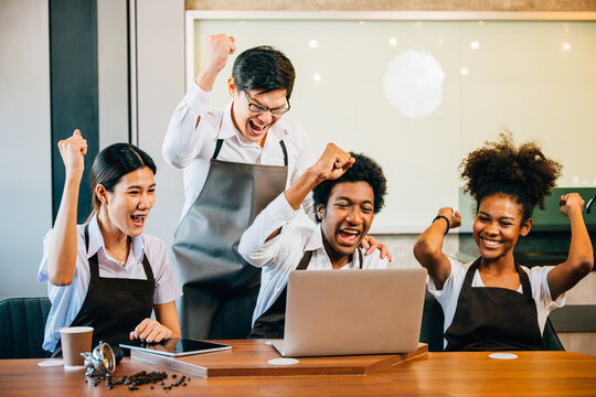 Diverse entrepreneurs have team meeting in stylish coffee shop. Barista owner discuss work on laptop. Multiethnic employees successful teamwork business strategy discussion.