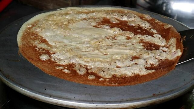 Asian Indonesian adult's hand cooking leker, thin and crispy Indonesian pancake, a sweet and savory treat, popular Indonesian street food 