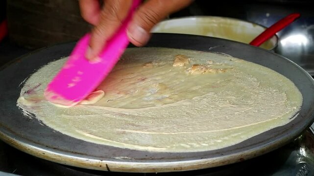 Asian Indonesian adult's hand cooking leker, thin and crispy Indonesian pancake, a sweet and savory treat, popular Indonesian street food 