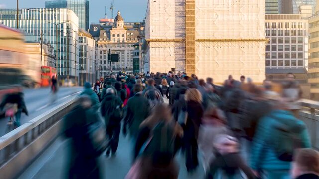 Tme lapse view of crowds of blurred motion commuters on London Bridge rushing into the City offices during sunrise