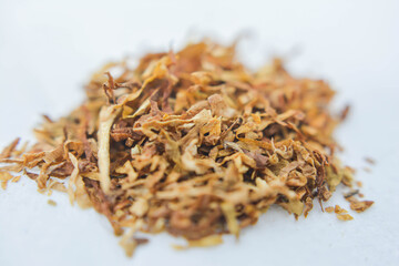 Dried tobacco on white background, closeup of a pile of tobacco. Heap of dried tobacco leaves. Dried chanterelle mushroom. Dried grass.

