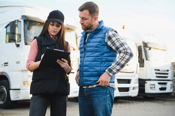 Logistics - proud driver or forwarder and female coworker, in front of trucks and trailers, on a transshipment point, its a good and successful team