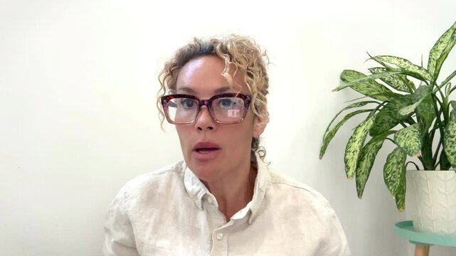 A mother with tied curly hair and glasses questions her son about his bad academic performance, addressing family dynamics, report cards, and disciplinary issues.