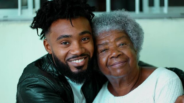 Portrait of South American black 20s grandson with elderly gray hair grandmother in tender embrace, 80s age of intergenerational bond, close-up faces of latin people of African descent