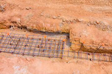 Construction work in progress with rebar grid laid in trench at site, showcasing groundwork for...