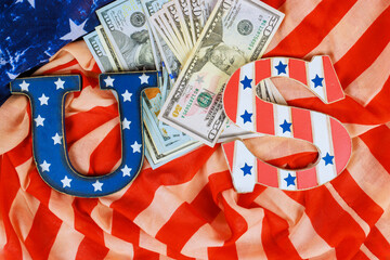 Colorful US letters sit on textured American flag with crisp dollar bills cash, creating festive finance vibe