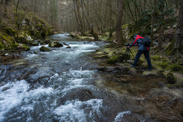 A nature photographer photographs a mountain river and its rapids. Photo of a mountain river and its surroundings.
