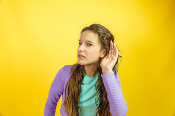 cute little girl try listening carefully by putting her hand to ear