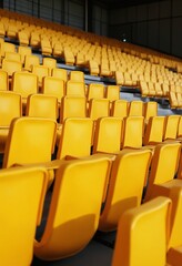 Naklejka premium Yellow tribunes. seats of tribune on sport stadium. empty outdoor arena. concept of fans. chairs for audience. cultural environment concept. color and symmetry. empty seats. modern stadium