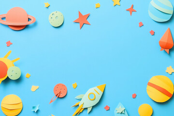 Fototapeta premium Colorful paper cutouts of planets, stars, and a rocket on a blue background.