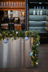Christmas decoration for restaurant, shopping mall, retail store, grocery with blue and white glass spheres, leafy plants arrangement and chain lights on the display