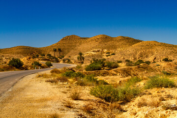 A winding asphalt road in the low mountains of Jebel Matmata. Matmata, Tunisia, Africa