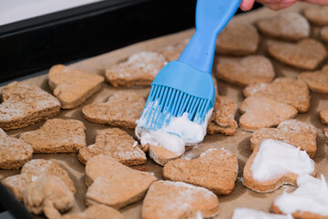 woman making heart shaped cookies in the kitchen, using silicon culinary brush