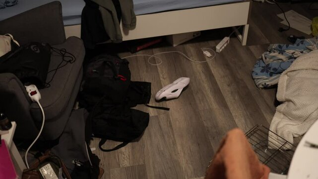 Messy room interior with scattered bags, a shoe, and various items on the floor, reflecting disorganization and everyday clutter in a lived-in space.