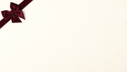 Luxurious maroon velvet bow on cream background for elegant holiday themes or luxury products