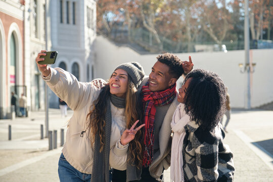Group of cheerful multiracial friends taking selfie while walking down the street