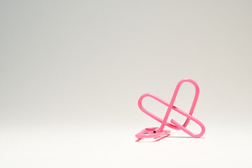 Fototapeta premium Un clip rosa con forma de corazon en un fondo blanco.