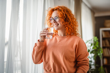 portrait of redhead adult woman drink water in the living room