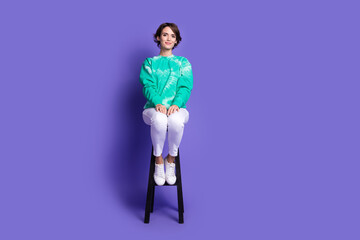 Full size photo of attractive young woman sit chair dressed stylish green clothes isolated on violet color background