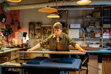 Handyman joiner makes custom table from solid wood in shop workshop. Precision craftsmanship,...