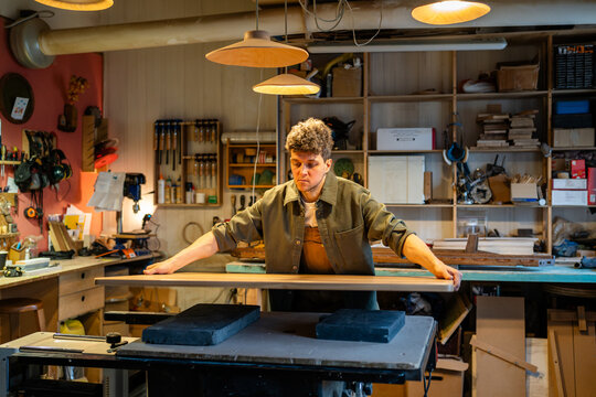 Handyman joiner makes custom table from solid wood in shop workshop. Precision craftsmanship, custom design, handcrafted furniture, durable materials, tailored piece, manual labor, furniture making