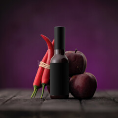 Apple chili hot sauce in bottle on wooden table. Cayenne pepper and red apples sweet sauce. Barbecue sauce. Chili Apple Glaze, Jam. Chutney. Salsa. Spicy Food. Purple background. Copy space.