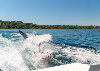 Young Athlete Falling Off Wake Surf Board in Red Life Vest