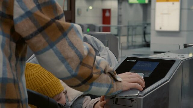 Multitasking parent navigating urban mobility, using smartphone for contactless subway ticket payment while managing baby stroller at station platform