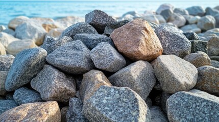 Granite beach stones arranged in a pile with the ocean in the background, captured in soft natural lighting.