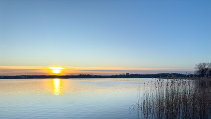 Tranquil lake at sunset, a peaceful, reflective lake surface in winter.