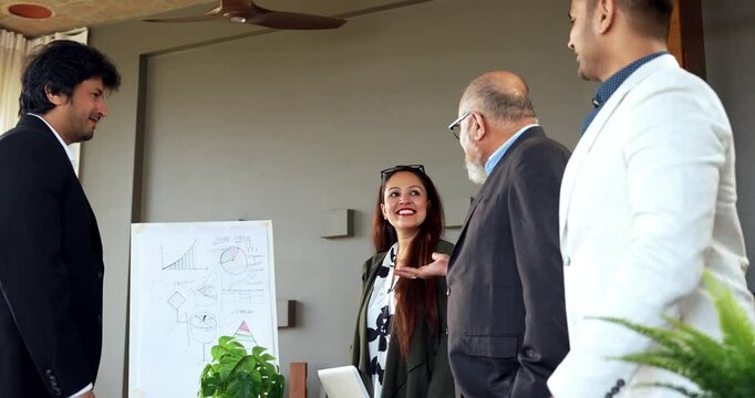 Indian Asian young business professional or businessman confidently shaking hands across a table with a colleague after finalizing a significant business deal or new project in modern corporate office