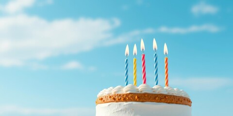 Classic birthday cake with simple yet colorful candles against a calm and serene blue sky background, peaceful, traditional, natural