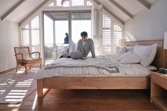 Man using laptop on bed