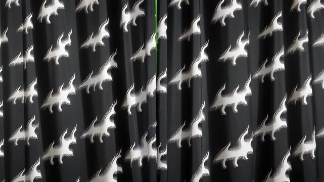 Dino-mite Drapes: Close-up of dark fabric with a repeating pattern of stylized dinosaur silhouettes. Perfect for adding a playful touch to any child's room. 
