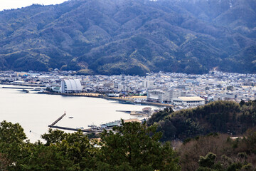 Obraz premium Coastal Cityscape with Mountains and Harbor View