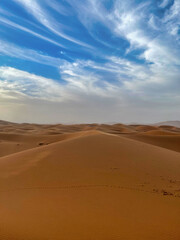 red sand dunes and cloudy blue sky in erg chebbi desert, Morocco