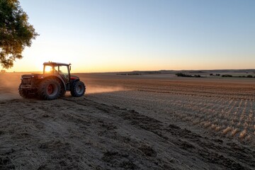 Obraz premium The image captures a tractor leaving a trail of dust in a harvested cereal field, symbolizing the ongoing cycle of agriculture and the relationship between land and labor in farming.