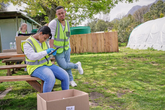 Female volunteer checking tablet during packaging donation boxes