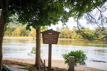 Serene Riverside with Informative Sign, Amanohashidate , Kyoto, Japan