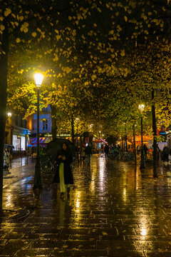 Woman holding umbrella at night in rain in Paris, France