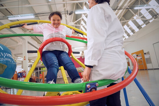 Teenager with down syndrome plying on gyroscope at science center