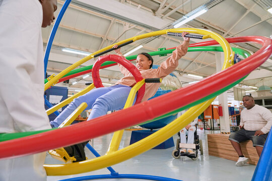Instructor assisting teenager at gyroscope in science center