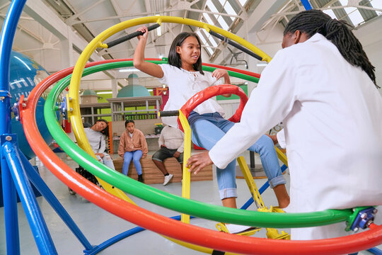 Instructor assisting teenager at gyroscope in science center
