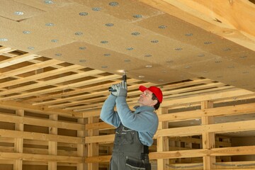 Fototapeta premium Construction worker thermally insulating eco wooden frame house