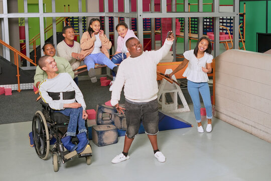 Teenage boy taking selfie with group of cheerful teenagers in science center