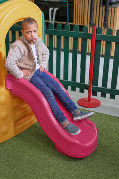 Sad boy sitting on slide in science center