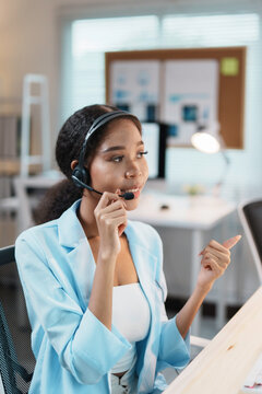 Confident Asian telemarketer woman working in call center talking on her headset explaining something to a customer