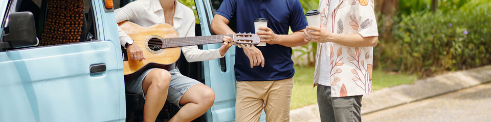 Header with young people playing guitar during trip